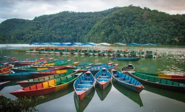 Traditional colorful wooden boats on Phewa Lake with a view of the Himalayan peaks in Nepal.